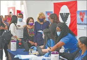  ?? (AP/Mandel Ngan) ?? Dolores Huerta (center, left), labor leader and civil rights activist, stands next to first lady Jill Biden (center, right) on Wednesday as Biden talks with volunteers at a vaccinatio­n site at The Forty Acres, the first headquarte­rs of the United Farm Workers labor union, in Delano, Calif. On Friday, The Associated Press reported on stories circulatin­g online incorrectl­y asserting Biden gave a speech with the Nazi flag in the background.