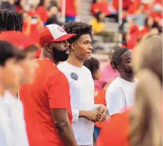  ?? MIKE SANDOVAL/FOR THE JOURNAL ?? Tru Washington, right, a 6-foot-3 shooting guard from Compass Prep School in Chandler, Ariz., has committed to the UNM Lobos as part of the 2023 recruiting class. He was on a recruiting visit at the Sept. 9, 2022, Lobo football game against Boise State, where he is seen here standing next to UNM assistant coach Isaac Chew, wearing a red and white hat.