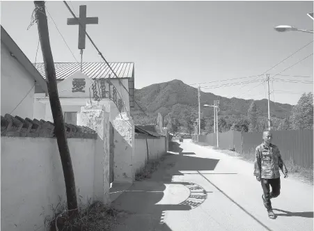  ??  ?? A man walks past a church at a border town in northeaste­rn China’s Jilin province. Missionari­es in northeaste­rn China are engaged in a dangerous work: Spreading Christiani­ty across the border to North Korea.