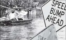  ??  ?? ESCAPE: Isaac (honest!) Fields and Victor Jones use traffic signs to paddle out of floods in LaPlace, La., yesterday.