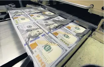  ?? AP ?? Uncut $100 bills run through cutting machine at the Bureau of Engraving and Printing Western Currency Facility in Fort Worth, Texas on Tuesday. The federal printing facility is making the new-look colourful bills that include new security features in...
