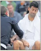  ??  ?? THAT’S OUT: Djokovic is treated