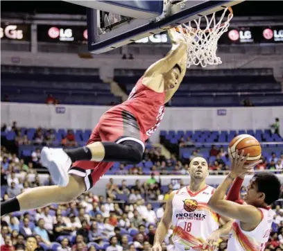  ?? (PBA media bureau) ?? GINEBRA’s Japeth Aguilar (left) hangs on the ring after scoring on a dunk against Phoenix during PBA action Friday at the Smart Araneta Coliseum. Phoenix won, 87-82. Aguilar is expected to play a bigger role against San Miguel Beer tonight since...