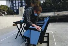  ??  ?? Hamilton Maletsky disinfects seats Thursday before the movie “John Lewis: Good Trouble” on the roof of 3Below Theaters & Lounge.