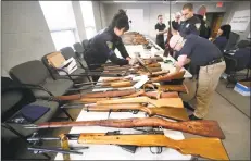  ?? Arnold Gold / Hearst Connecticu­t Media ?? New Haven Police Sgt. Charlette Barham, left, and Detective Josh Kyle, right, catalog rifles brought in during a gun buy-back Saturday at the New Haven Police Academy.