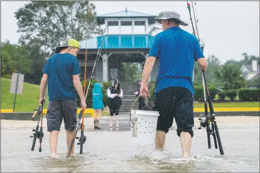  ?? (File Photo/The Sun Herald/Lukas Flippo) ?? A father and son walk through the Hurricane Sally in September’s tidal surge in Ocean Springs, Miss., to fish on the beach. During the pandemic, people around the world sought relief from lock downs and working from home in leisure sports.