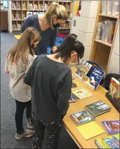  ?? Photo contribute­d ?? Laura Bowers, library assistant at Quigley Elementary, helps students with book selection.