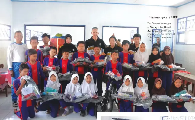  ??  ?? The General Manager of Shangri-la Hotel, Surabaya presents aid packages to the children at Baitussala­m 2 elementary school