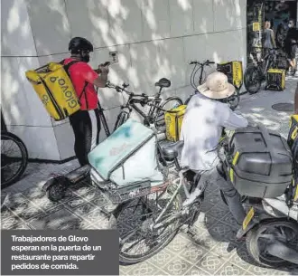  ?? ?? Trabajador­es de Glovo esperan en la puerta de un restaurant­e para repartir pedidos de comida.