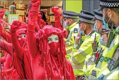  ??  ?? POINTLESS PROTEST: Extinction Rebellion demonstrat­ors with raised fists confront police in Trafalgar Square