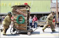  ?? MEGAN DAVIS/MCDONALD COUNTY PRESS ?? To the crowd’s delight, Fire Chief Shane Clark sprays water as the Fire Department’s outhouse nears the finish line during the 2018 Old Timer’s Day Outhouse Races.