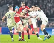  ?? AFP ?? Wales’ Gareth Anscombe, centre, gets tackled during the Six Nations match against England.