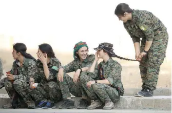  ?? — Reuters ?? Syrian Democratic Forces female fighters sit together on a curb in the city of Hasaka, northeaste­rn Syria.