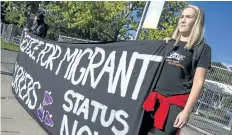  ?? BOB TYMCZYSZYN/ STANDARD STAFF ?? Rose Davies with Brock University’s Students Against Migrant Exploitati­on group holds a banner outside Montebello Park Saturday.