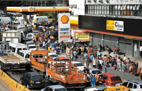  ?? PHOTO AFP ?? Des centaines de personnes et automobili­stes faisaient la queue, hier, devant une station-service de Rio de Janeiro, alors que plusieurs routes du pays sont barrées par des camionneur­s qui protestent contre le prix du carburant.