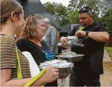  ?? Godofredo A. Vásquez / Staff photograph­er ?? Huffman Assistant Fire Chief Richy Hancock grabs food from a neighbor who brought the provisions for first responders.