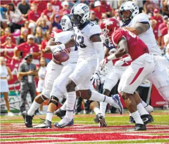  ?? THE ASSOCIATED PRESS ?? TCU running back Sewo Olonilua slips past Arkansas defender Josh Liddell to score a touchdown in the first half Saturday in Fayettevil­le, Ark. TCU rolled to a 28-7 victory.