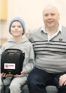  ?? TROY FLEECE ?? 10-year-old Benjamin Fizzard, along with his father Sheldon, holds an AED inside Ecole Wascana Plains School in Regina. Benjamin suffered a cardiac incident at Wilfrid Walker school and his family raised money through a GoFundMe account to buy an AED...