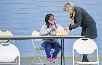  ?? [CHRIS LANDSBERGE­R/ THE OKLAHOMAN] ?? Ginny Bass Carl, executive director of Community CARES Partners, right, helps Cyneka Ingram fill out paperwork in December for the eviction mitigation program, which provided money for housing assistance to help clients pay their rent and utilities.