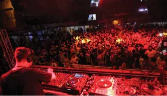  ??  ?? A deejay (DJ) mixes tracks as youths attend an electronic dance music event, during the annual Baghdad Summer Festival.