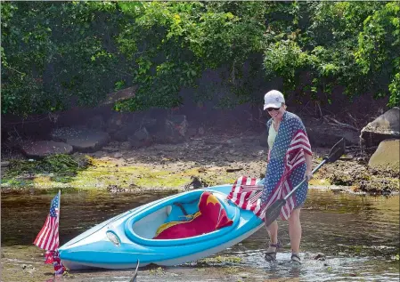  ??  ?? Above, Betsy Perkins of Waterford pulls her kayak back into deeper waters during a flotilla along Alewife Cove on Wednesday. About 50 people, most of them residents of the Ridgewood neighborho­od of Waterford, participat­ed in the annual Fourth of July event.