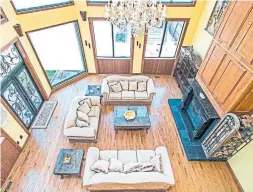  ?? COLDWELL BANKER R.M.R. REAL ESTATE PHOTOS ?? A cathedral ceiling, hardwood floor, wood-burning fireplace with floor-to-ceiling wood surround, and soaring windows are features of the living room.