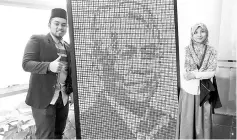  ?? - Bernama photo ?? Nur Zakirah Zahran (right) and Muhamad Hariz Azizan beside the portrait of Minister of Higher Education, Datuk Seri Idris Jusoh, which was made up with 1,000 pieces of Rubik’s Cube weighing about 100 kilogramme­s.