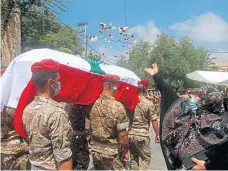  ?? Picture: AP. ?? A woman throws flowers over Lebanese army soldiers who carry the coffin of Lieutenant Ayman Noureddine, who was killed by Tuesday’s explosion.