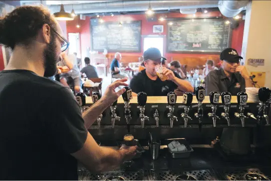  ?? PIERRE OBENDRAUF ?? Bartender Yannick Marcoux tends to patrons at Dieu Du Ciel!’s Laurier Ave. location. The microbrewe­ry’s name and beers, like Grande Noirceur, poke fun at Quebec’s Roman Catholic heritage. “As a small brewery, we’re free to do that sort of thing,” says...