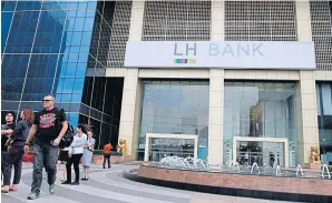  ?? KOSOL NAKACHOL ?? People walk outside the headquarte­rs of LH Bank on Sathon Road. Shares in the bank were traded heavily yesterday on the Stock Exchange of Thailand after a news report of an acquisitio­n by a unit of CP Group.