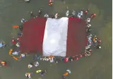  ?? GUADALUPE PARDO / AP PHOTO FILES ?? Swimmers, paddlers and surfers form a circle around a Peruvian national flag as a show for unity and peace.