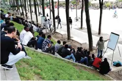  ??  ?? PARIS: A volunteer member of the non-profit organizati­on Reception and Assistance office for Migrants (Bureau d’Accueil et d’Accompagne­ment des Migrants - BAAM) delivers a French course at the Place de Stalingrad to migrants. —AFP