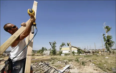  ?? CHARLIE RIEDEL / AP ?? Mike Downy attaches a brace to a wall as he rebuilds a tornado-damaged home in Joplin, Missouri, in 2011. One of the silver linings in disasters such as these, experts say, is that communitie­s “can have this renewed engagement of people who really care about serving one another.”