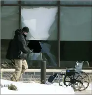  ?? DAVID JOLES — STAR TRIBUNE VIA AP ?? Law enforcemen­t personnel walk past a broken window outside of the Allina Health clinic Tuesday in Buffalo, Minn.