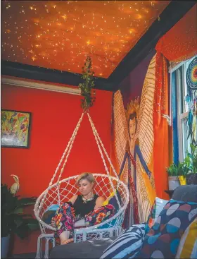  ??  ?? Berry, who has lived in New York City since 2004, from Laurel, Md., sits in a hammock swing in her living room decorated with her artwork July 6 in New York.