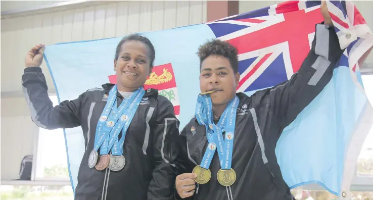  ?? Photo: Peni Komaisavai ?? Team Fiji Weightlift­ers Apoloni Vavai (right) and Maria Liku raising the Fiji Flag and showcasing their medals from the Pacific Mini Games at the Epauto Hall, Port Vila, Vanuatu on December 6, 2017.