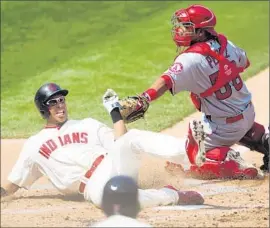  ?? Jason Miller Getty Images ?? CLEVELAND’S Michael Brantley is safe at home as Angels catcher Carlos Perez misses the tag during the first inning. The Angels lost, 9-2, and fell to 65-65, the first time they’ve been at .500 since June 26, when they were 37-37.