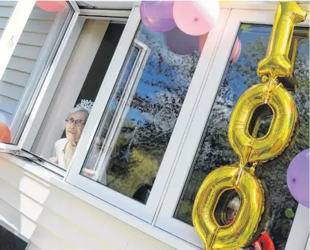  ?? KEITH GOSSE THE TELEGRAM ?? Phyllis Cooper, 100, peers outside the window of her unit at Caribou Manor in Pleasantvi­lle Wednesday afternoon. Cooper turned 100 on Wednesday and was visited by friends and family who wished her a happy birthday from outside the home.