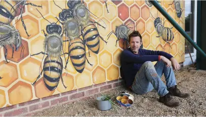  ?? Picture: Reuters ?? BEE THERE. US artist Matthew Willey next to a mural of bees at Pipers Corner School in Buckingham­shire as part of his Good of the Hive project to paint 50 000 bees on buildings around the world.