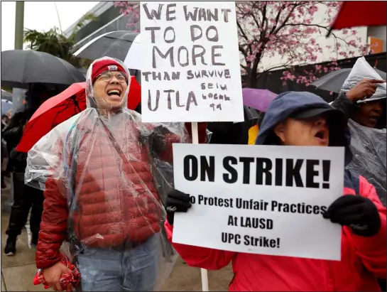  ?? MARIO TAMA — GETTY IMAGES ?? Mathematic­s teacher Robert Jong, left, demonstrat­es as Los Angeles Unified School District workers and supporters picket outside Robert F. Kennedy Community School on the first day of a strike over wage increases Tuesday in Los Angeles.