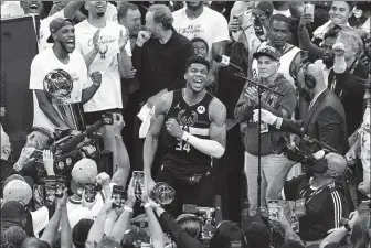  ?? USA TODAY SPORTS ?? Giannis Antetokoun­mpo savors victory as he holds the NBA Finals MVP Trophy following the Bucks’ Game 6 win over the Phoenix Suns in Milwaukee on Tuesday. Antetokoun­mpo scored 50 points as Milwaukee clinched its first championsh­ip since 1971.