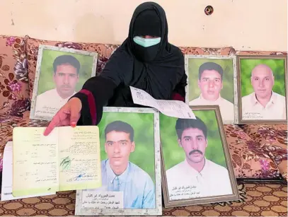  ?? REUTERS ?? Una mujer enseña el certificad­o de muerte de uno de sus hermanos, asesinado por milicia Kaniyat