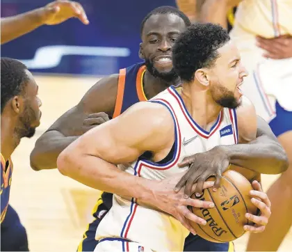  ?? JEFF CHIU/AP ?? The 76ers’ Ben Simmons, foreground, is grabbed by the Warriors’ Draymond Green Tuesday night in San Francisco.