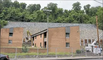  ?? Darrell Sapp/Post-Gazette ?? The rocky hillside and retaining wall that supports the new section of Route 30 can be seen behind the remaining parts of the Electric Avenue Apartments on Electric Avenue.