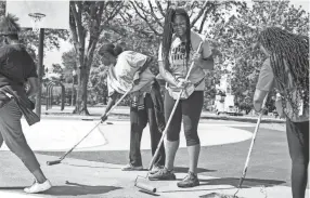  ??  ?? Madison Turner, 13, smiles while helping other children and volunteers paint the Greenlaw Park basketball court on Wednesday. BRAD VEST/THE COMMERCIAL APPEAL