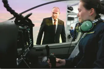  ?? MIKHAIL METZEL/POOL ?? Russian President Vladimir Putin looks on as a pilot sits in the cockpit of a flight simulator March 7 at a military aviation school in Krasnodar, Russia.