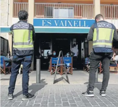  ?? ISAAC BUJ / EFE ?? Dos agentes de la Policía Nacional durante un control en una terraza de un restaurant­e de Palma de Mallorca.