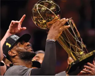  ?? JOSE CARLOS FAJARDO/TRIBUNE NEWS SERVICE ?? Above: LeBron James (23) hoists the Larry O'Brien Trophy after his Cavaliers defeating the Warriors in Game 7 of the NBA Finals on June 19 at Oracle Arena in Oakland. Below: James (23) shoots over the Raptors' Bismack Biyombo (8) during the playoffs in...