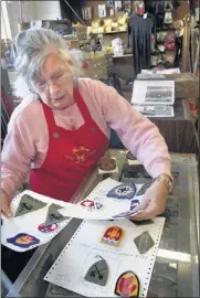  ??  ?? Mary Klug sorts military patches at Army Surplus Colliervil­le, which the family has operated for three decades near the town square.