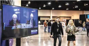  ?? ?? People walk past a screen Saturday with a live view of Berkshire Hathaway CEO Warren Buffett (left) and Vice Chairman Charlie Munger at the Berkshire Hathaway Shareholde­rs Meeting in Omaha, Nebraska.